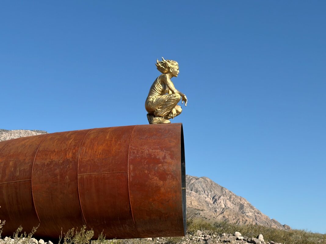 Mujer de rasgos asiáticos sentada sobre un caño oxidado en el Valle de Zonda, San Juan, durante una intervención artística de Martín Di Girolamo