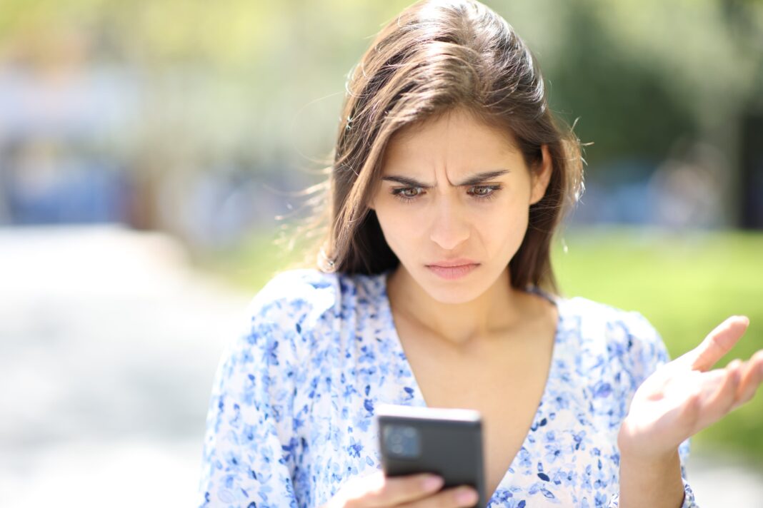 Persona sosteniendo un teléfono móvil con un símbolo de escudo de seguridad digital superpuesto.