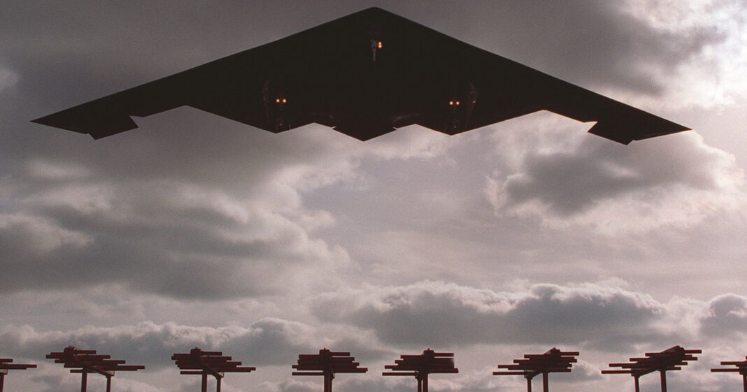 Bombardero furtivo B-2 Spirit en vuelo junto a cazas F-35C sobre un portaaviones.