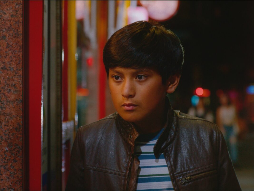 Fotograma de la película 'El tren fluvial' mostrando al protagonista, Milo Barria, en un entorno que mezcla el campo y la ciudad.