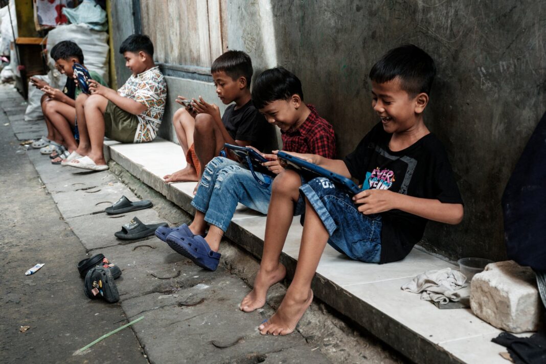 Niños en un callejón de Yakarta utilizando smartphones y tablets, días antes de la entrada en vigor de la nueva ley digital.