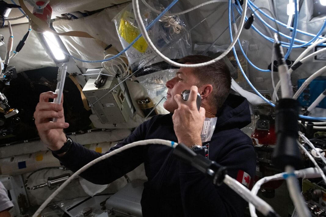 Astronauta de la NASA sosteniendo un iPhone 17 Pro Max en el interior de la cápsula espacial de la misión Artemis II.
