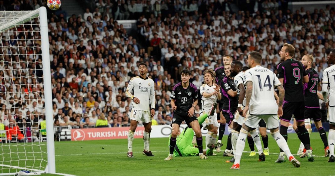 Escudos del Real Madrid y el Bayern Múnich con el trofeo de la Champions League de fondo.