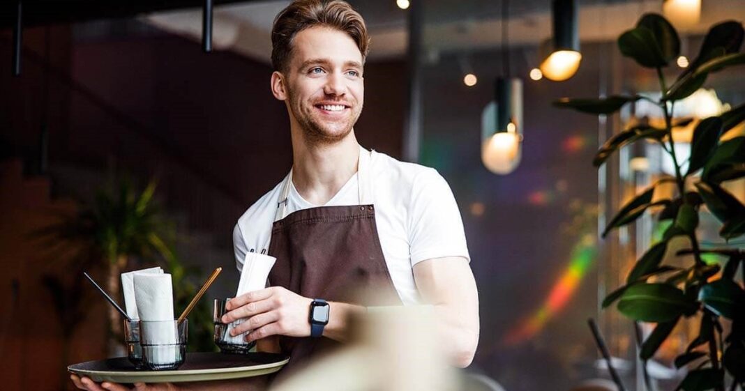 Mesero en un restaurante de Texas atendiendo a clientes, representando el análisis de ingresos por salario y propinas.