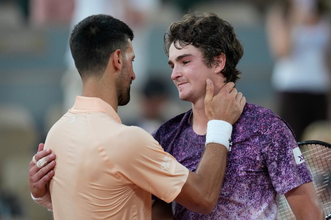 Joao Fonseca y Novak Djokovic se saludan en la red tras el partido en Roland Garros