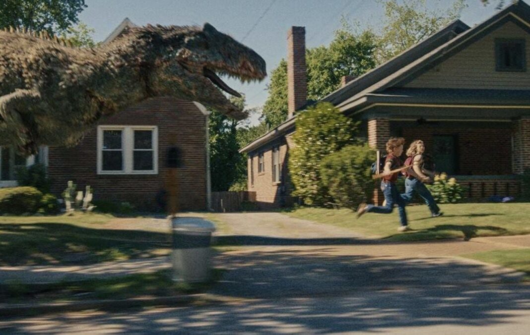 Póster de El final de Oak Street con Anne Hathaway y Ewan McGregor frente a un dinosaurio