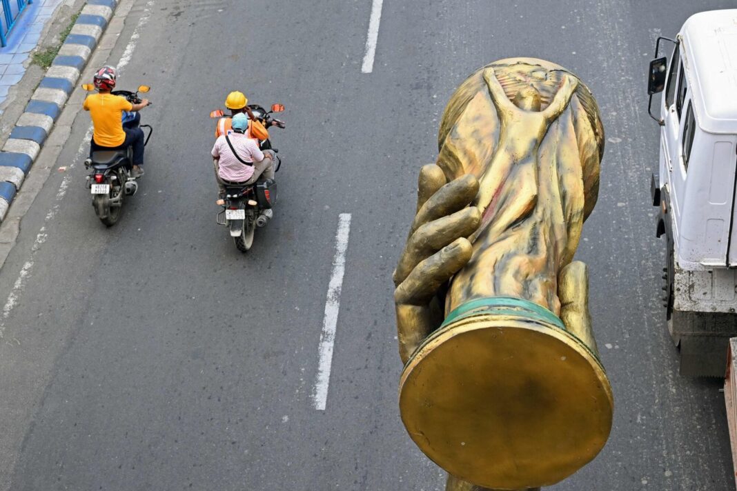Réplica del trofeo de la Copa Mundial de la FIFA sostenida por una escultura de Lionel Messi en Calcuta