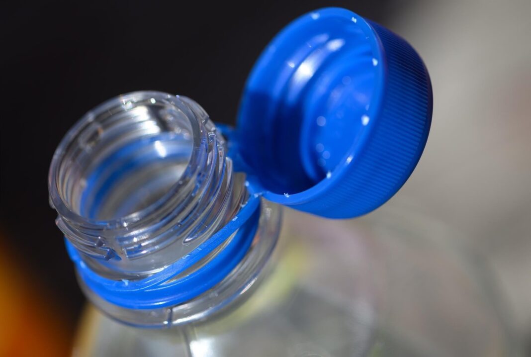 Botella de agua desechable de plástico blando sobre un fondo de estadio de fútbol