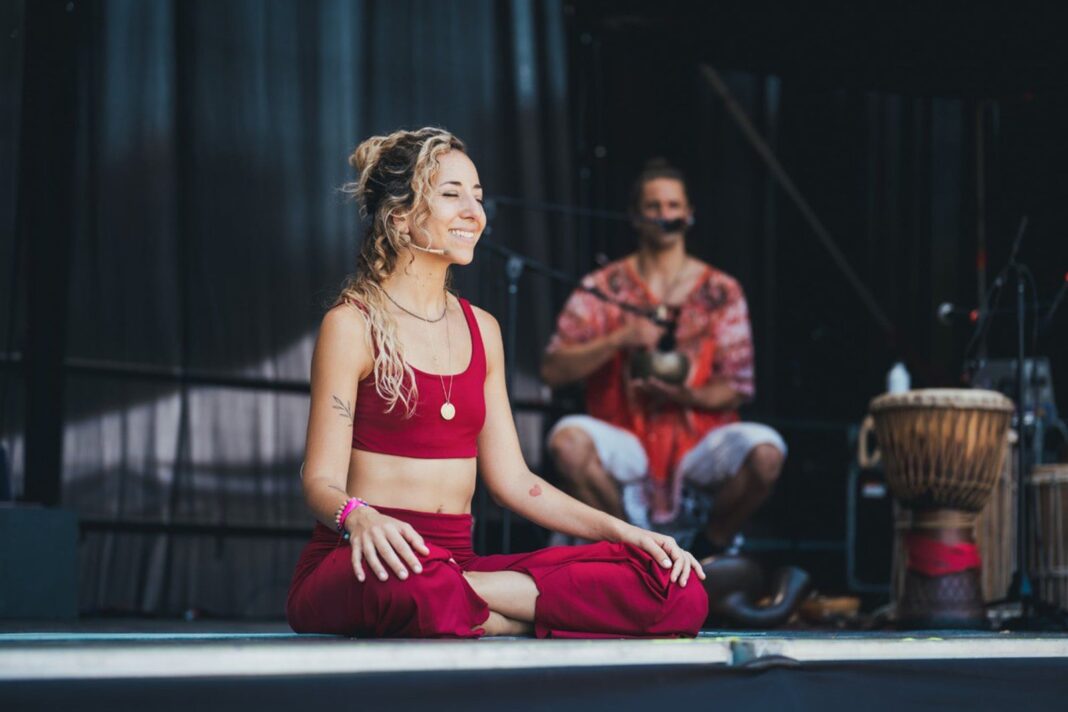 Personas practicando yoga al aire libre en un evento grupal