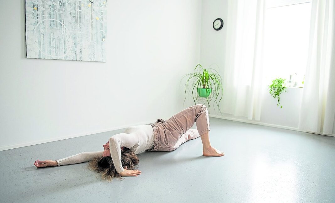 Persona realizando ejercicio del método Feldenkrais en el piso